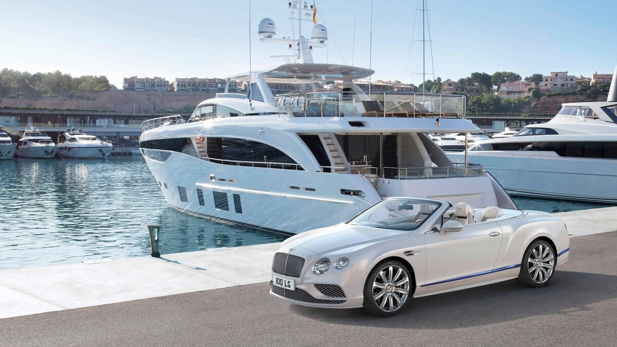 White bentley continental gt convertible at the pier next to expensive yachts