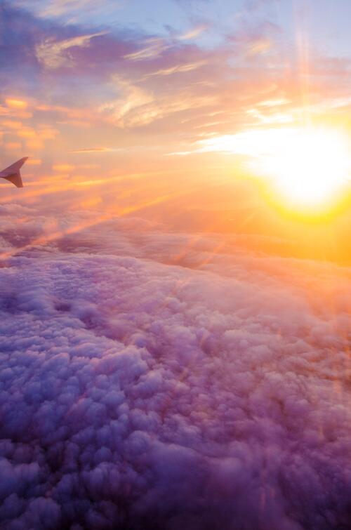 Flying an airplane over the clouds at sunset