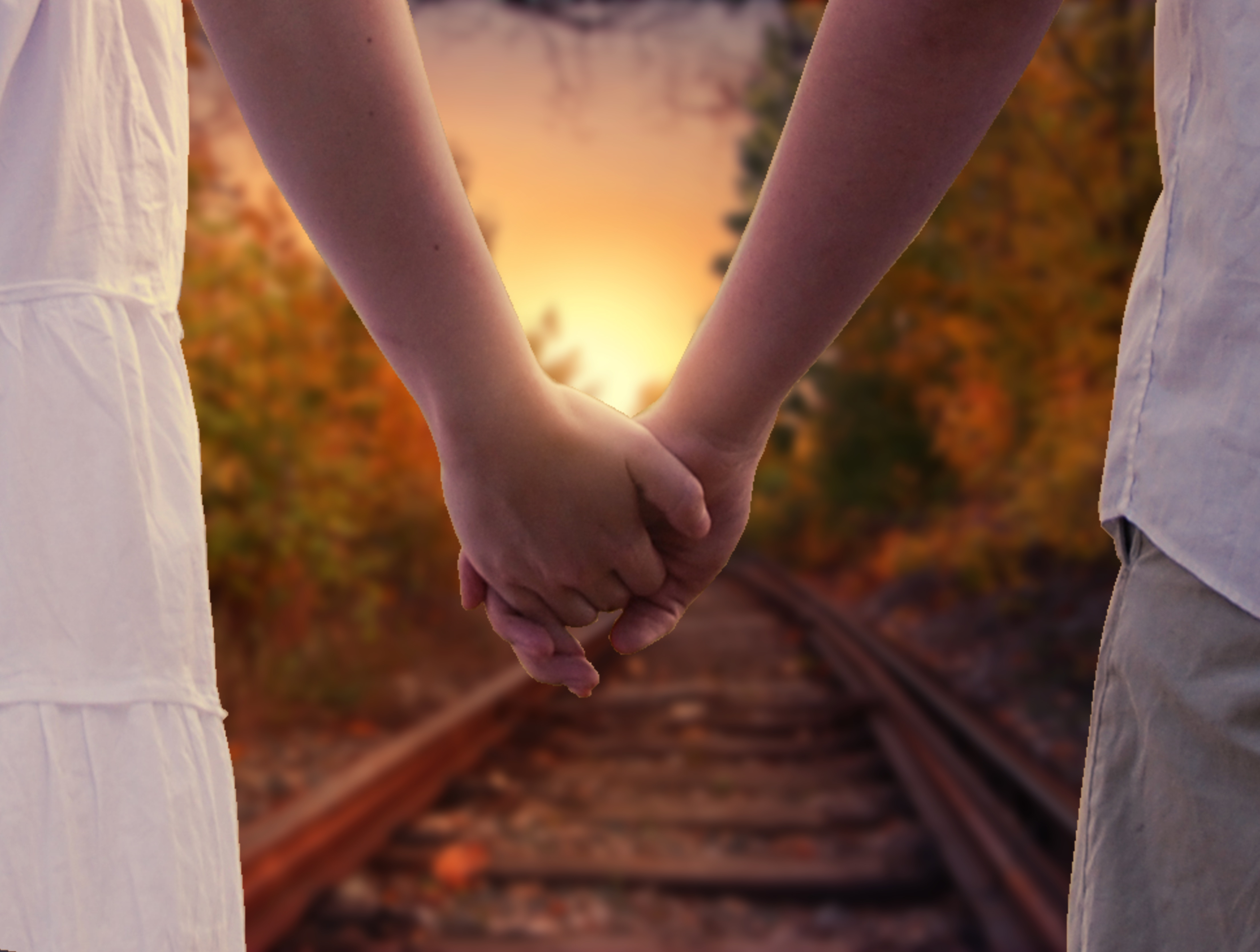 Free photo Young couple holding hands walking along the railroad tracks