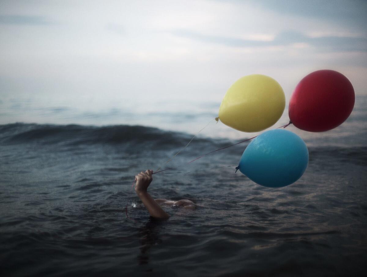 Плавает в море с воздушными шариками