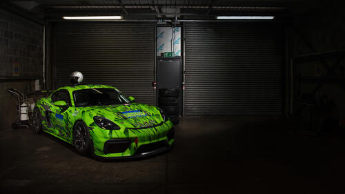 Салатовый Porsche Cayman стоит в темном гараже