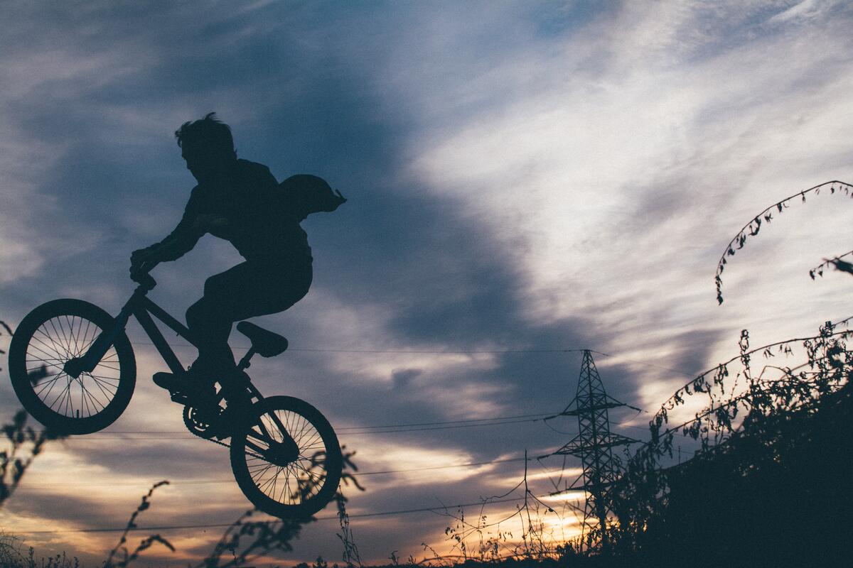 A silhouette of a boy on a bicycle against the sky
