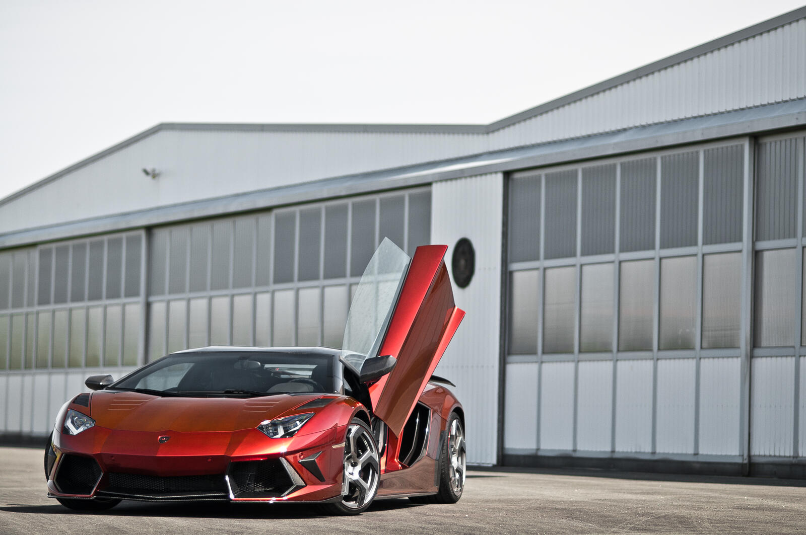 Free photo A red Lamborghini Aventador stands outside the large aircraft hangars with the door open