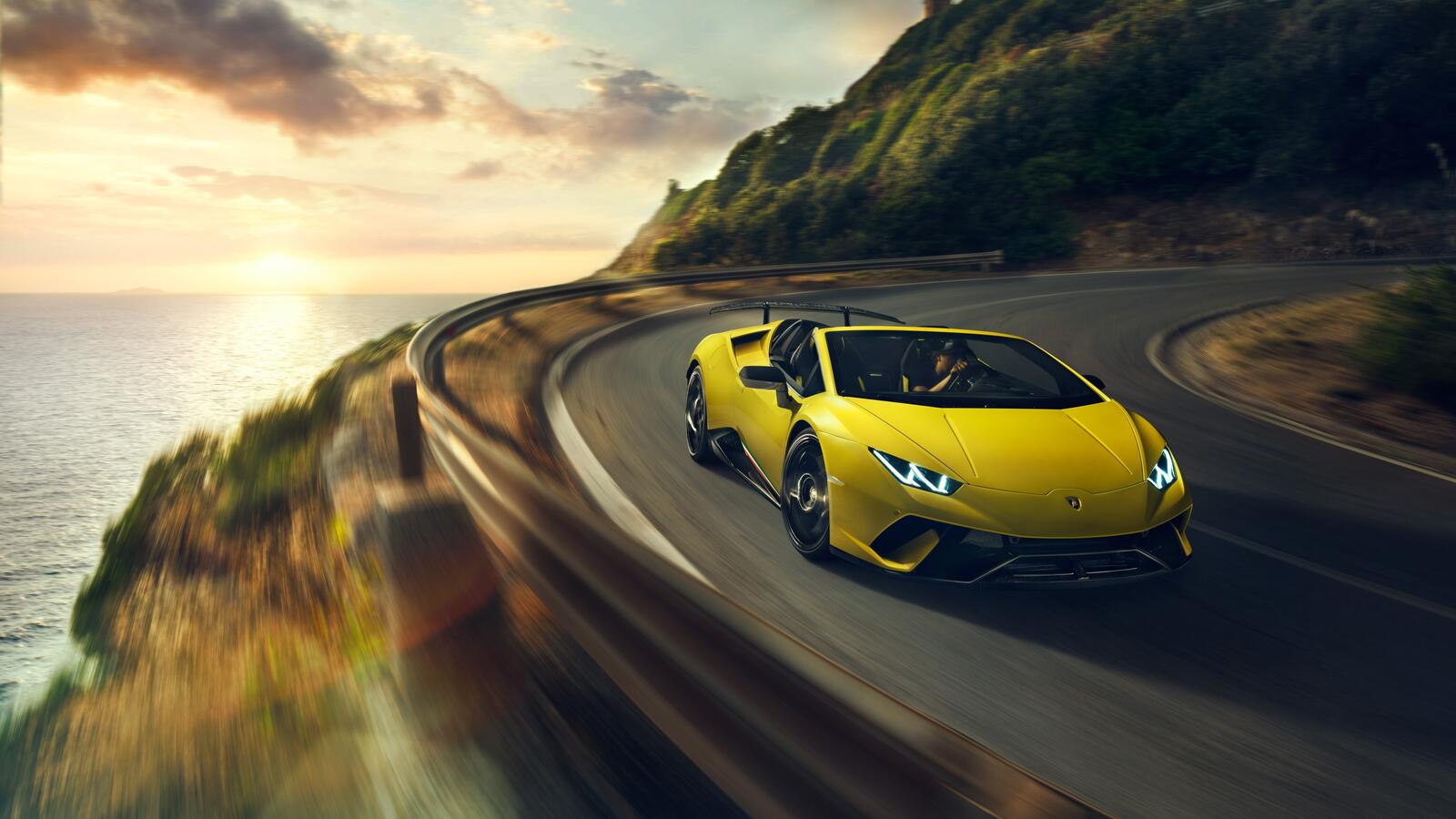 Бесплатное фото Желтая Lamborghini Huracan мчится по загородной дороге