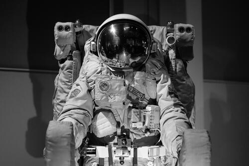 An astronaut sits in a chair in a black and white photo