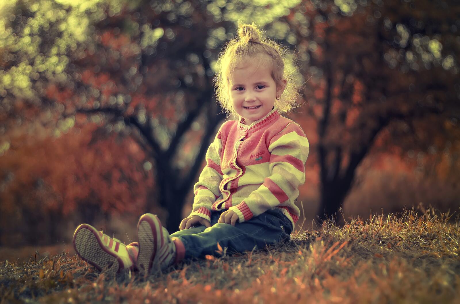 免费照片一个穿着高领毛衣的女孩坐在草地上。