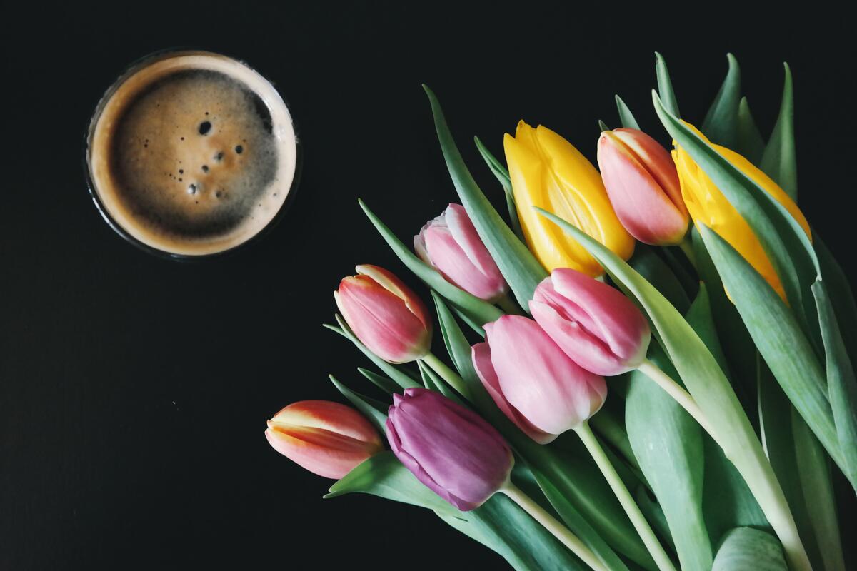 A bouquet of tulips with a cup of coffee.
