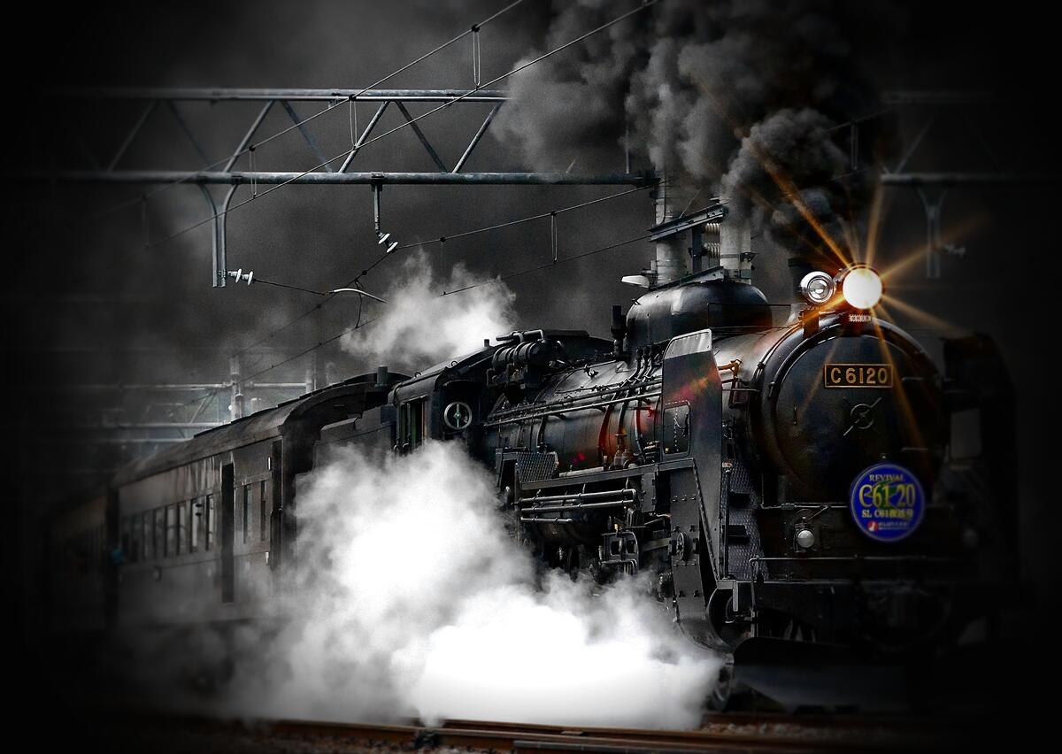 An antique steam locomotive with black smoke coming out of its chimney.