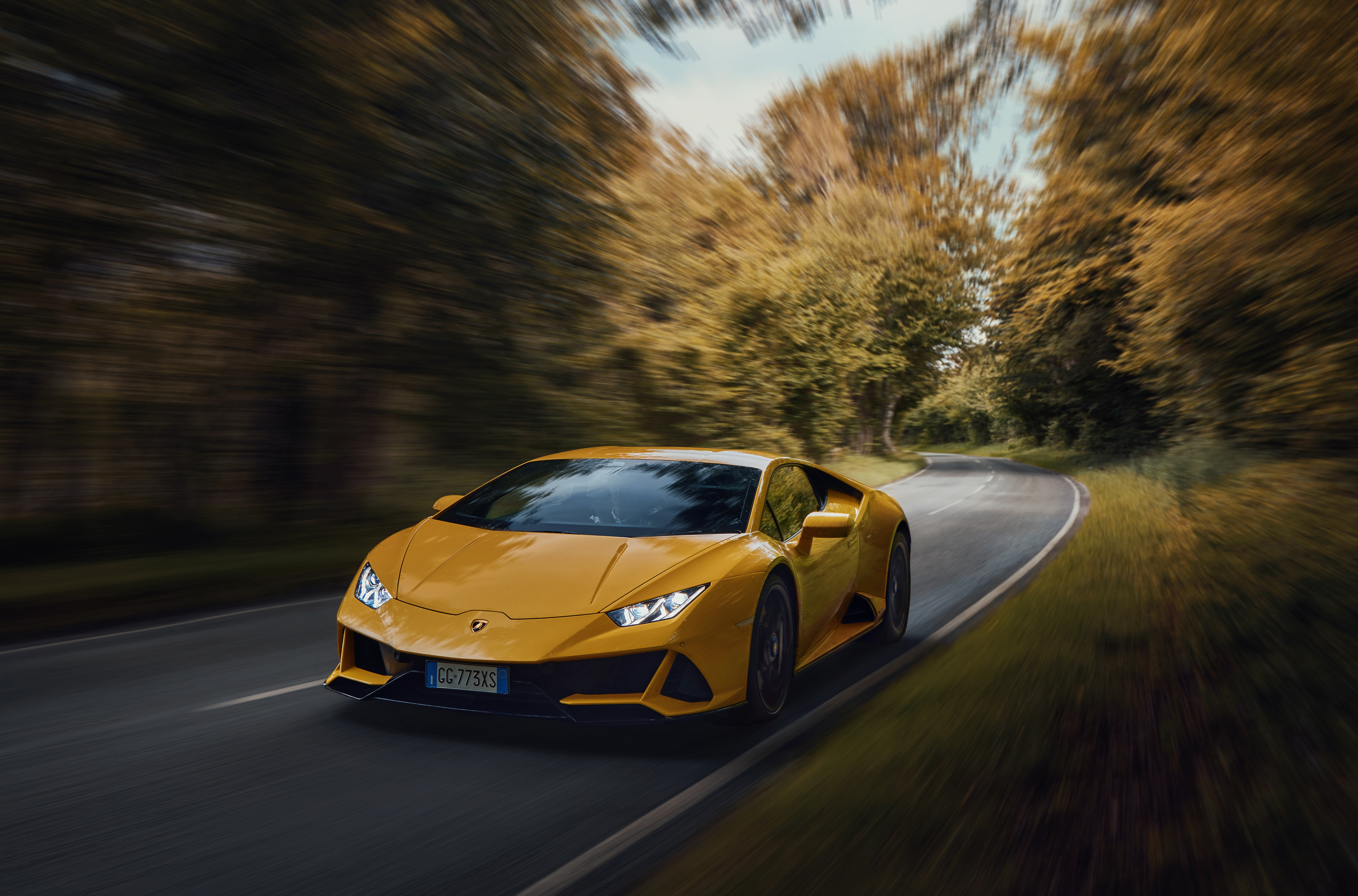 Lamborghini Huracan Evo 2022 года оранжевого цвета едет на высокой скорости по дороге