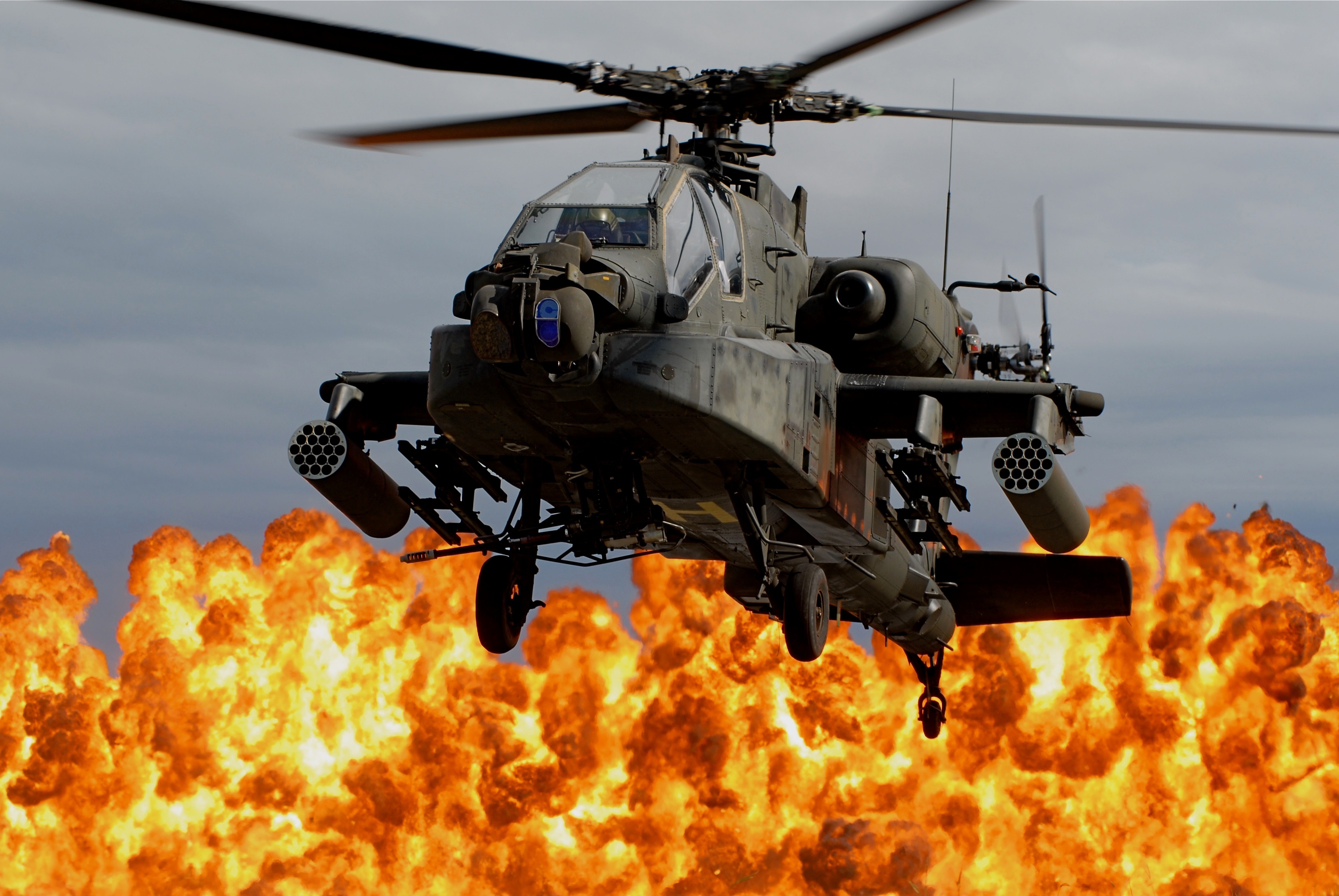 A military helicopter flies away from an explosion