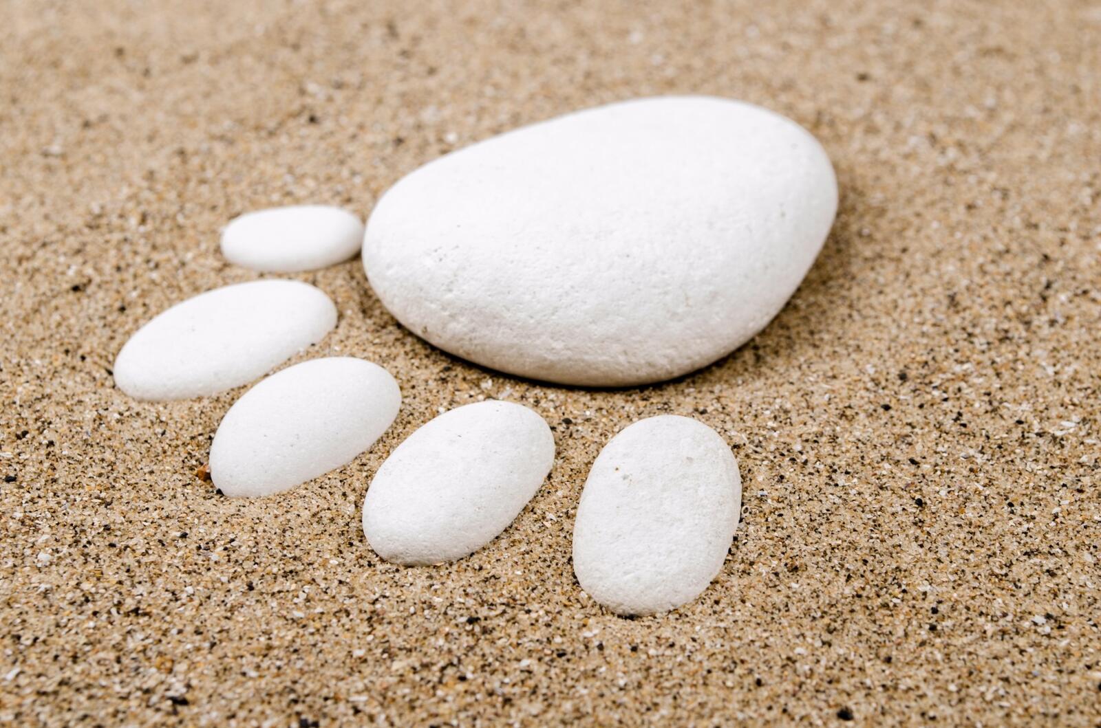 Белые камушки на пляже в виде ступни