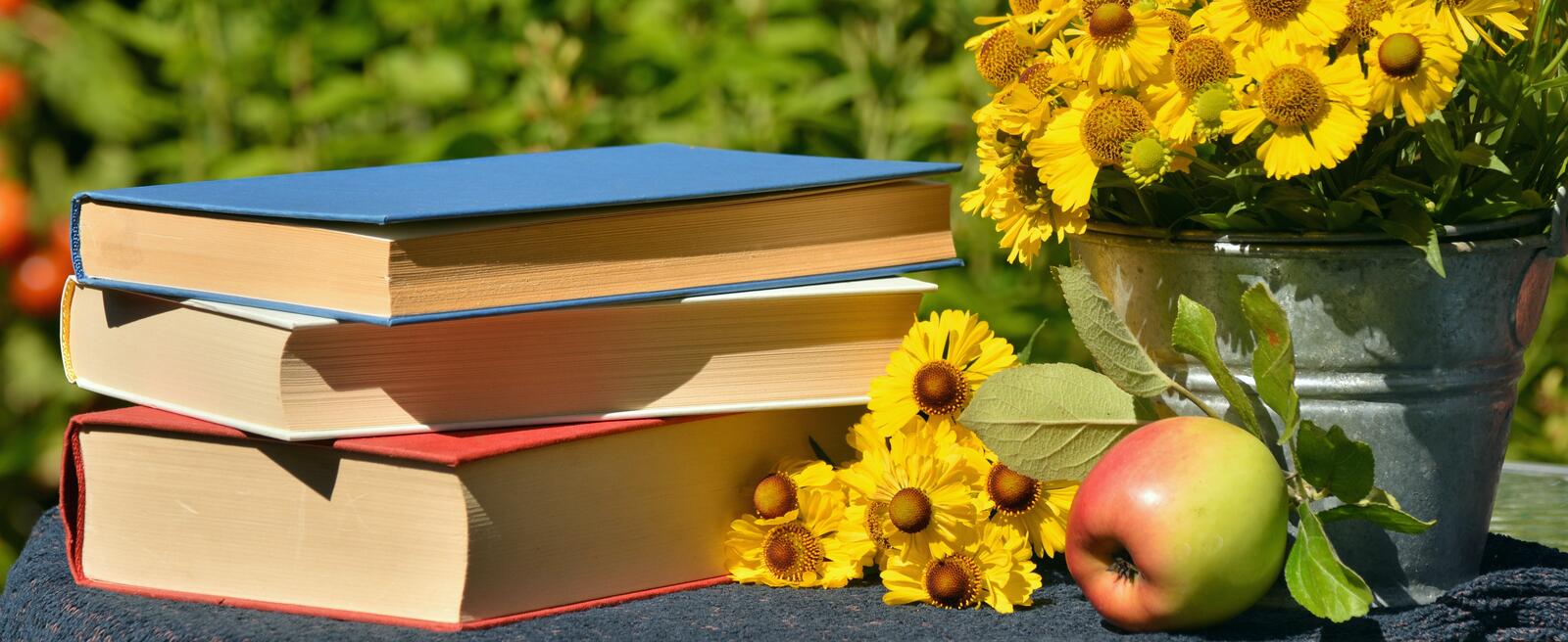 Free photo Yellow flowers in a bucket on a table of books