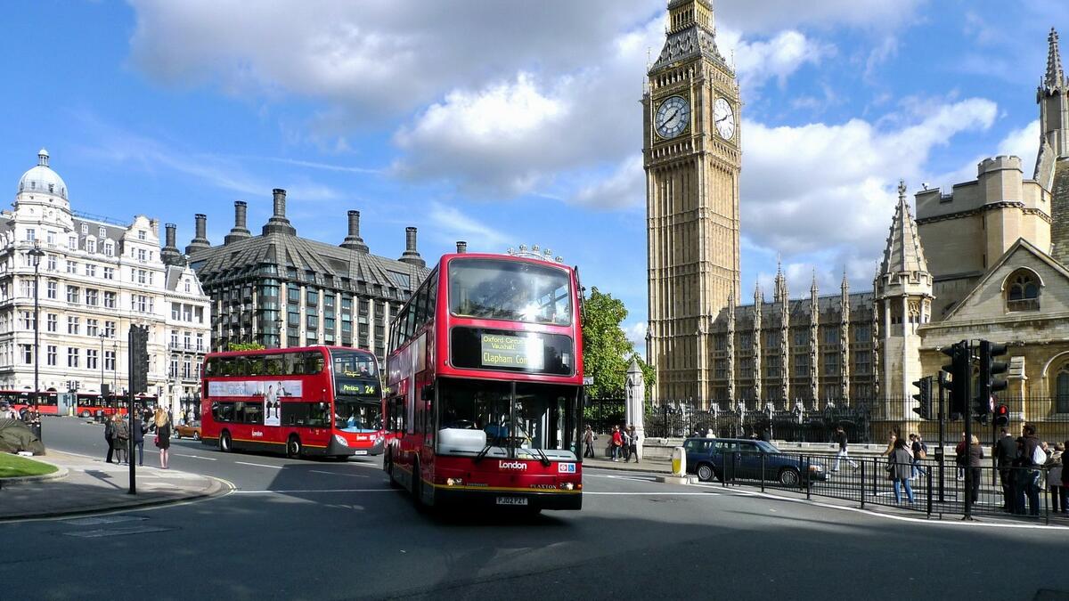 Красные автобусы едут на фоне биг бен в Лондоне