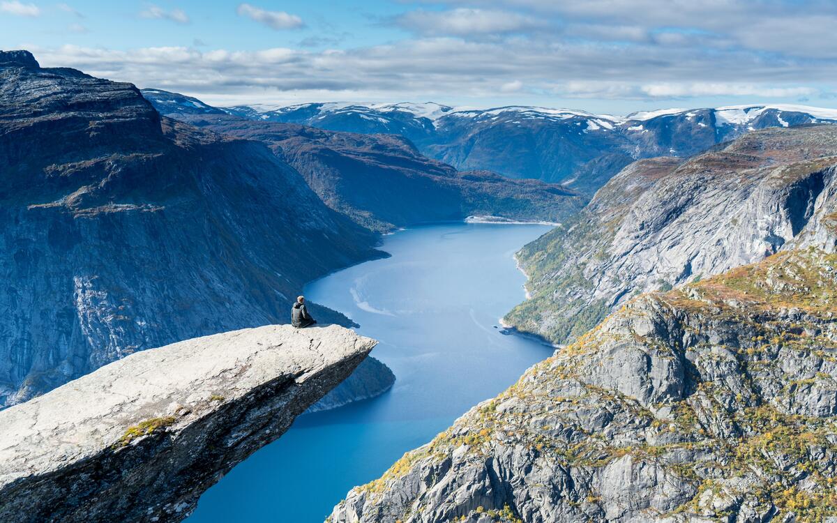 Мужчина сидит на скале над океаном в горах