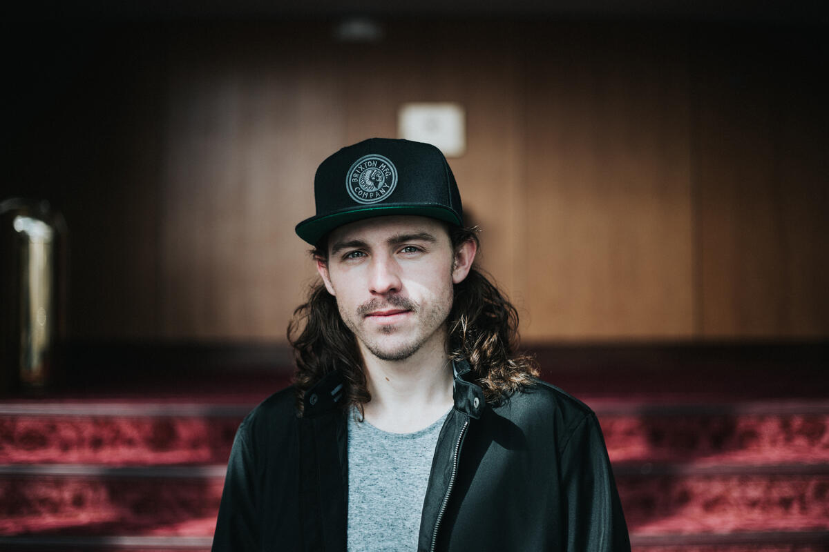 A long-haired musician in a cap.
