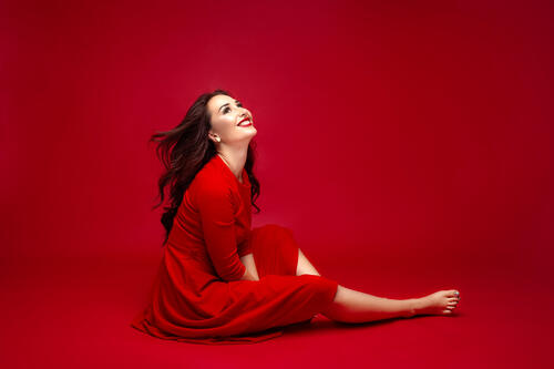 Очаровательная женщина в красном платье на красном фоне