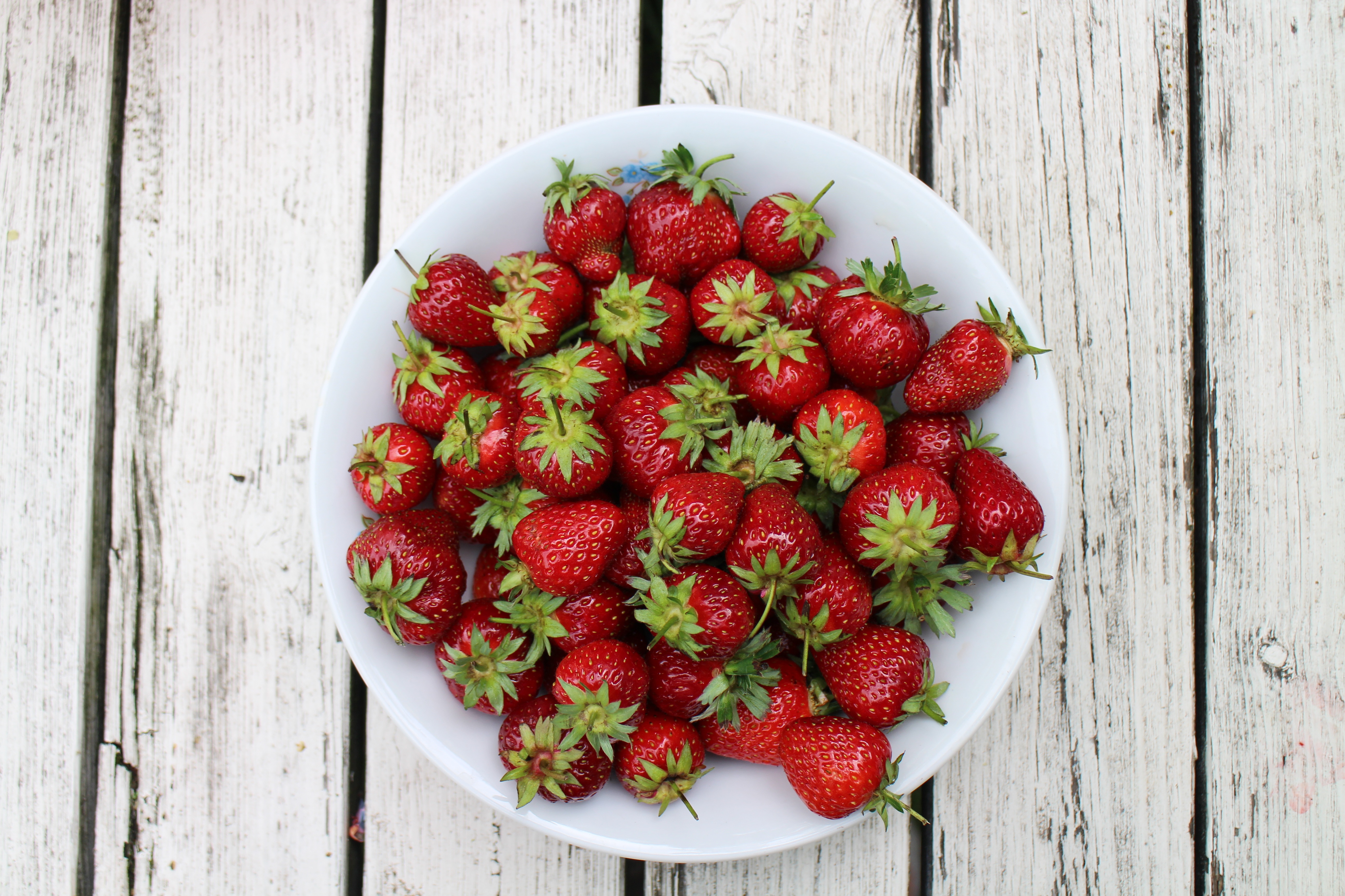 将草莓倒在白色盘子上，盘子上放着草莓堆