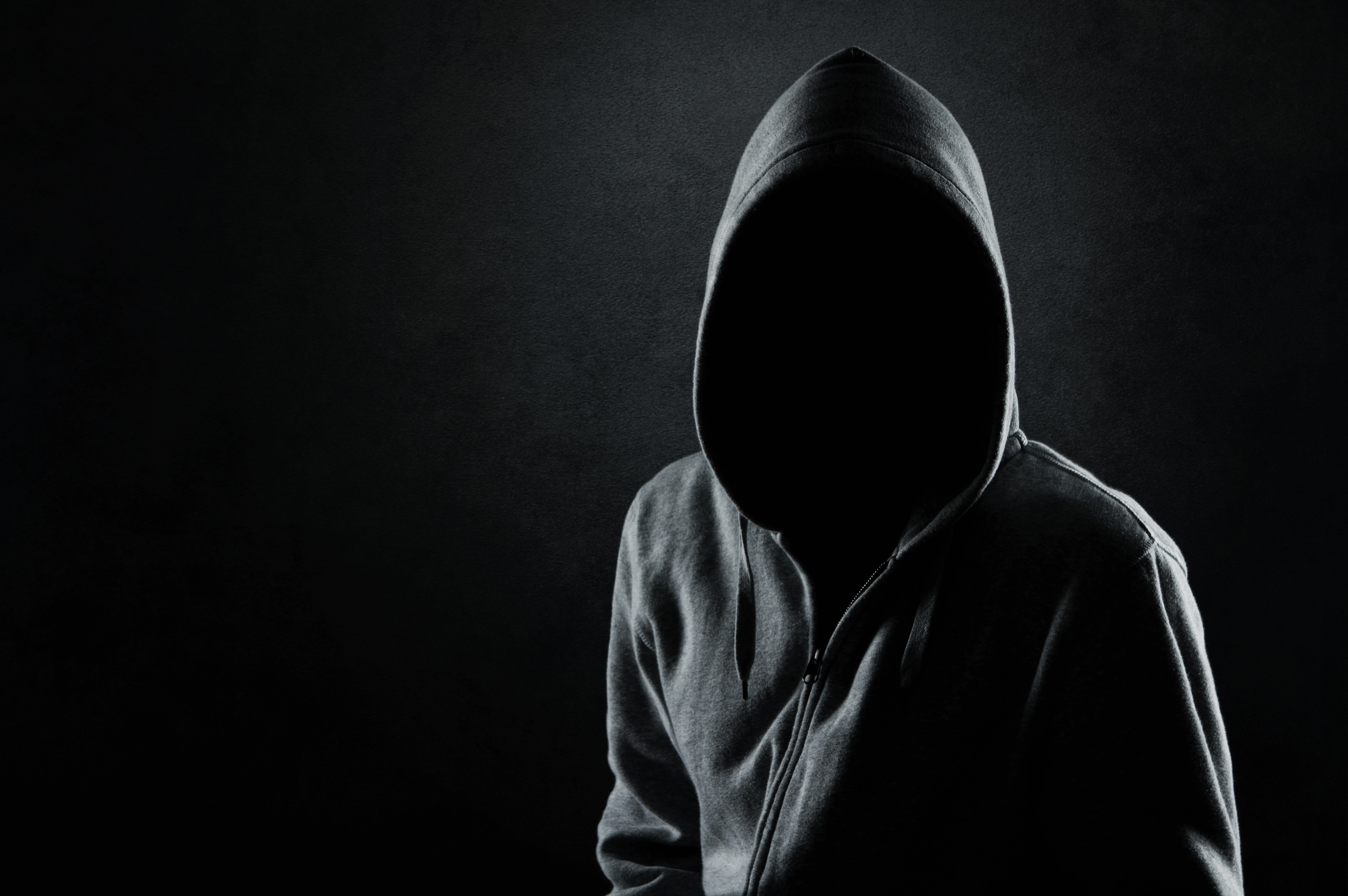 免费照片一个在黑暗中穿着连帽运动衫、面容隐秘的人。