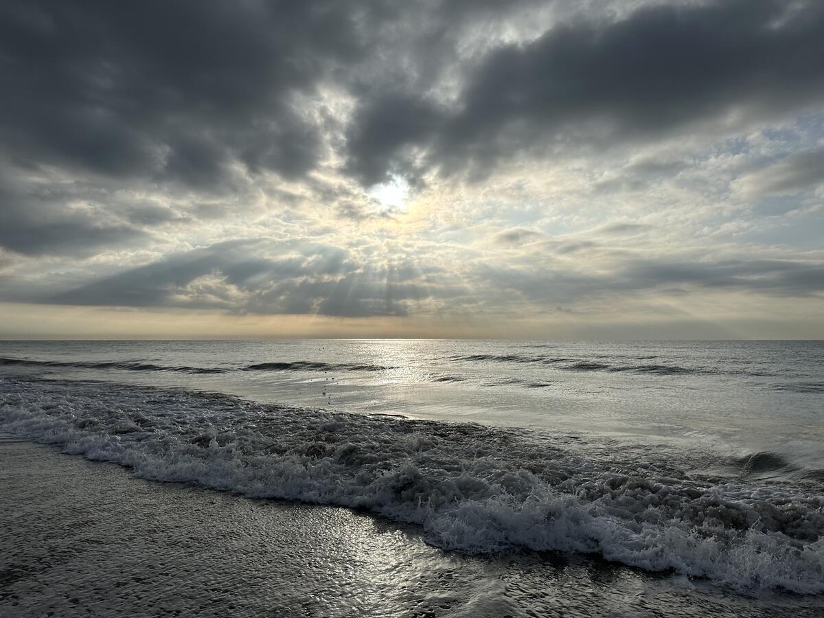 The sun in the clouds above the sea waves