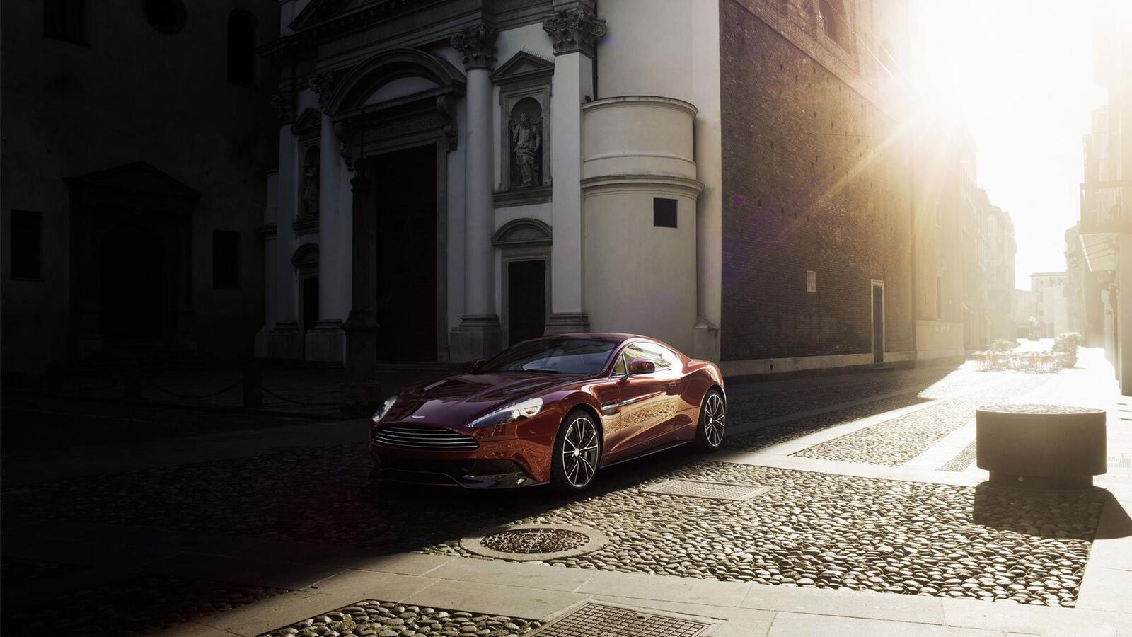 Бесплатное фото Aston Martin Vanquish едет по солнечной улице