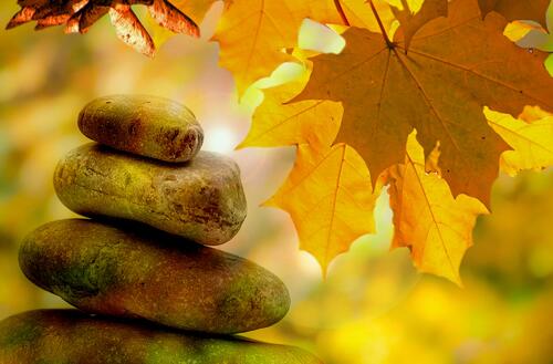 Камушки сложена друг на друга на фоне осенних листьев клена