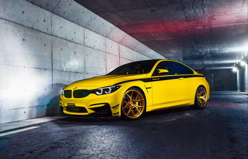 Yellow bmw m4 f82 on gold rims with a black stripe on the side