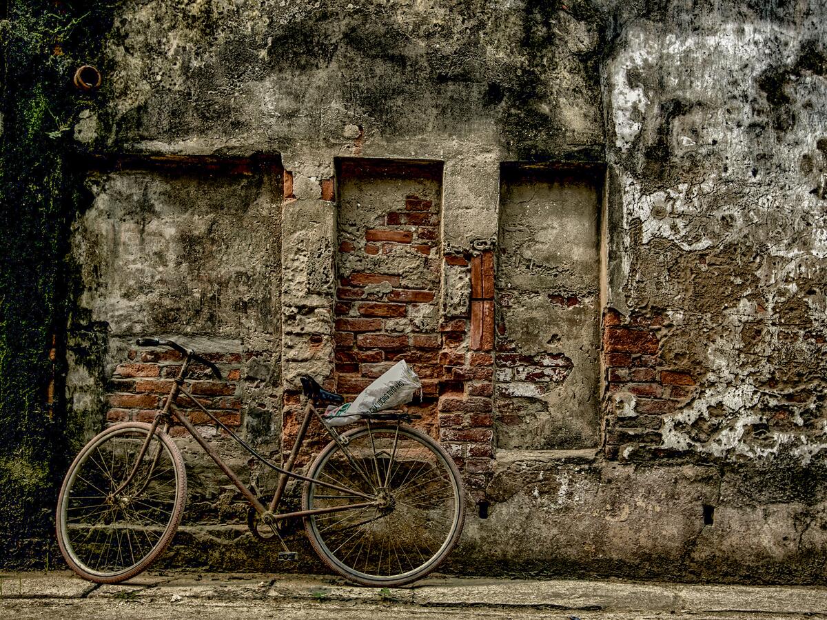 An old bicycle against a grim brick wall
