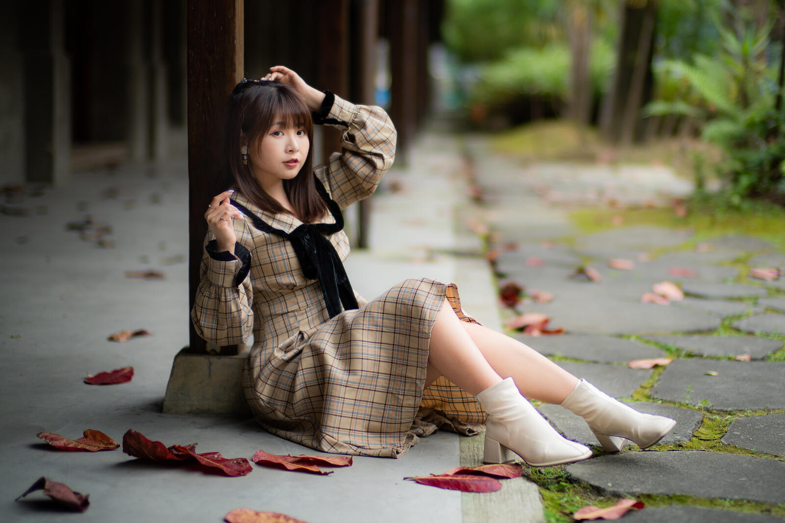 Бесплатное фото Азиатка сидит на бетоне рядом с опавшими листьями