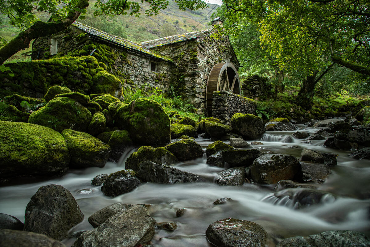 Abandoned watermill covered with green moss in England