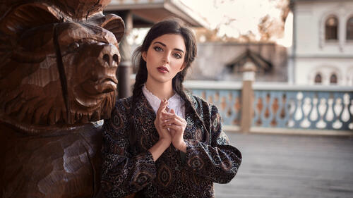 Симпатичная девушка у деревянной статуи медведя