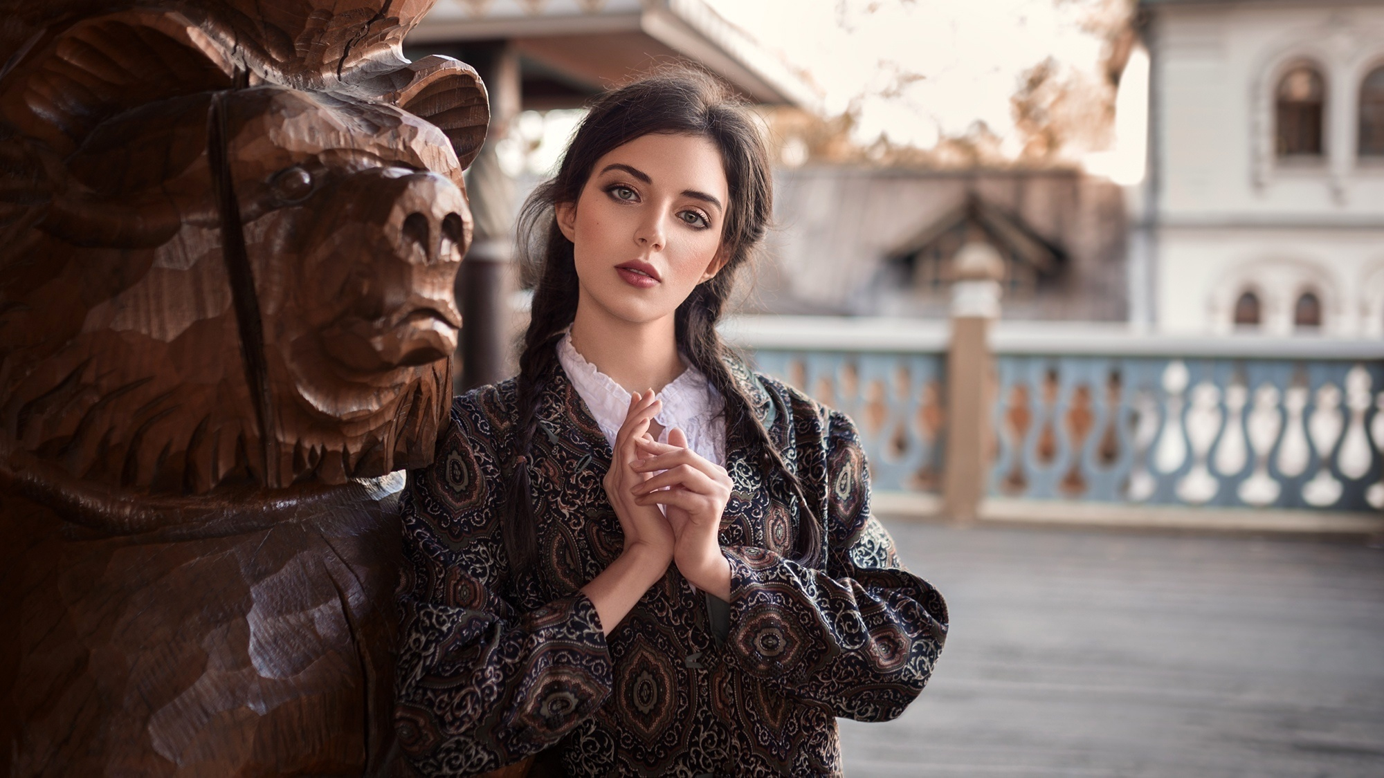 Бесплатное фото Симпатичная девушка у деревянной статуи медведя