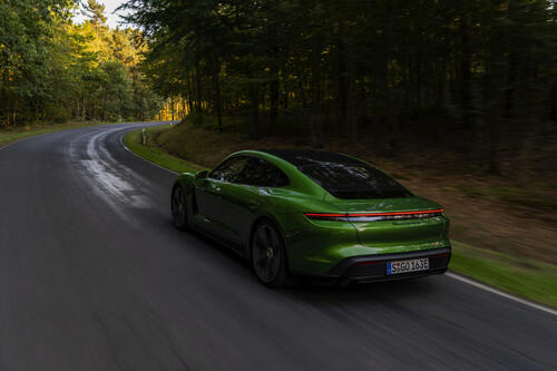 Green Porsche Taycan Turbo S rushes along a country road