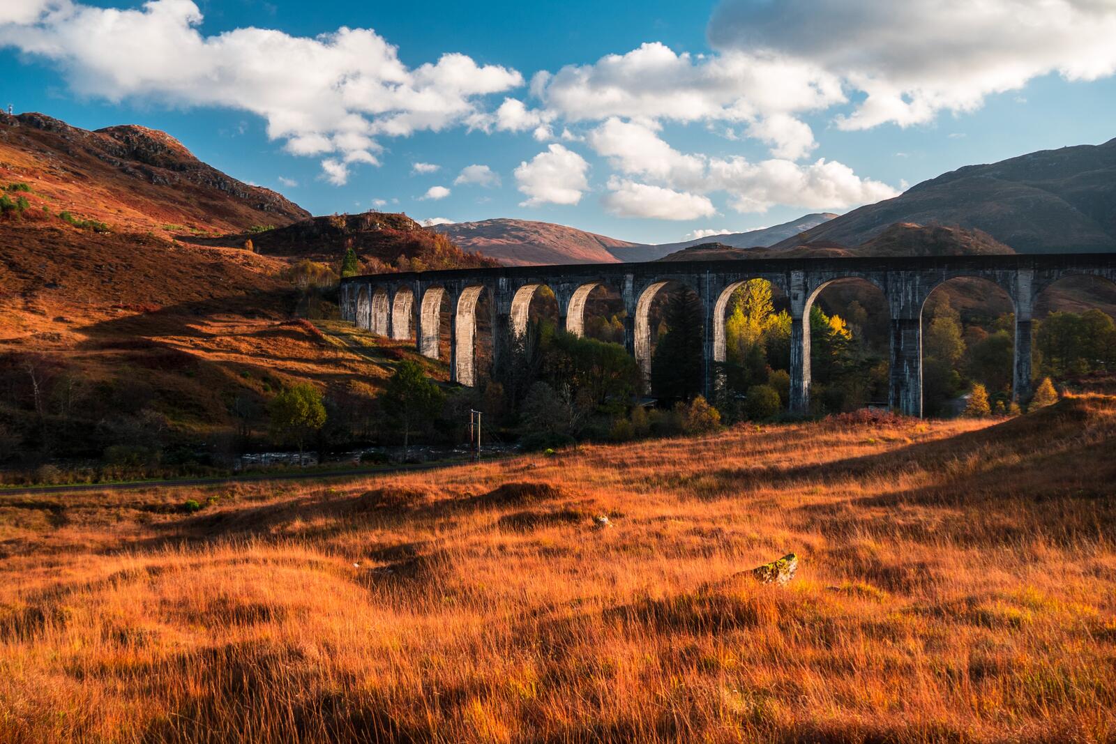Бесплатное фото Осенний пейзаж в горах с большим арочным мостом