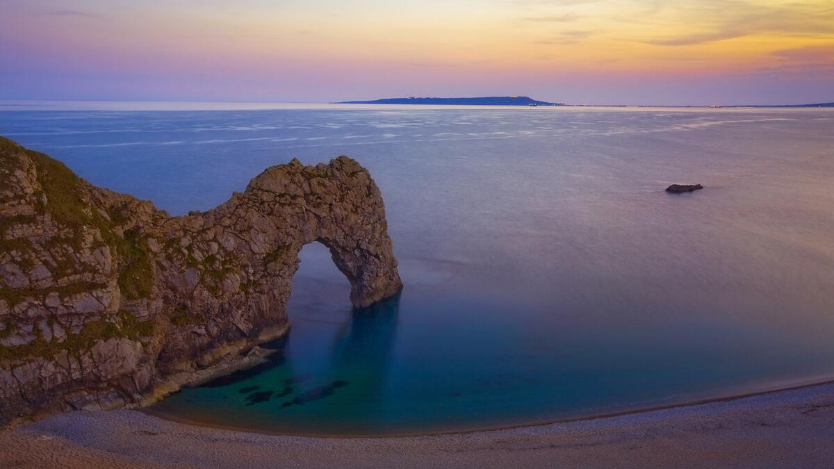 Скала на берегу пляжа с выступом в виде арки
