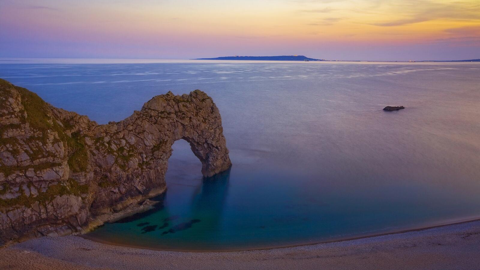 Free photo A rock on the shore of the beach with an arch-shaped ledge