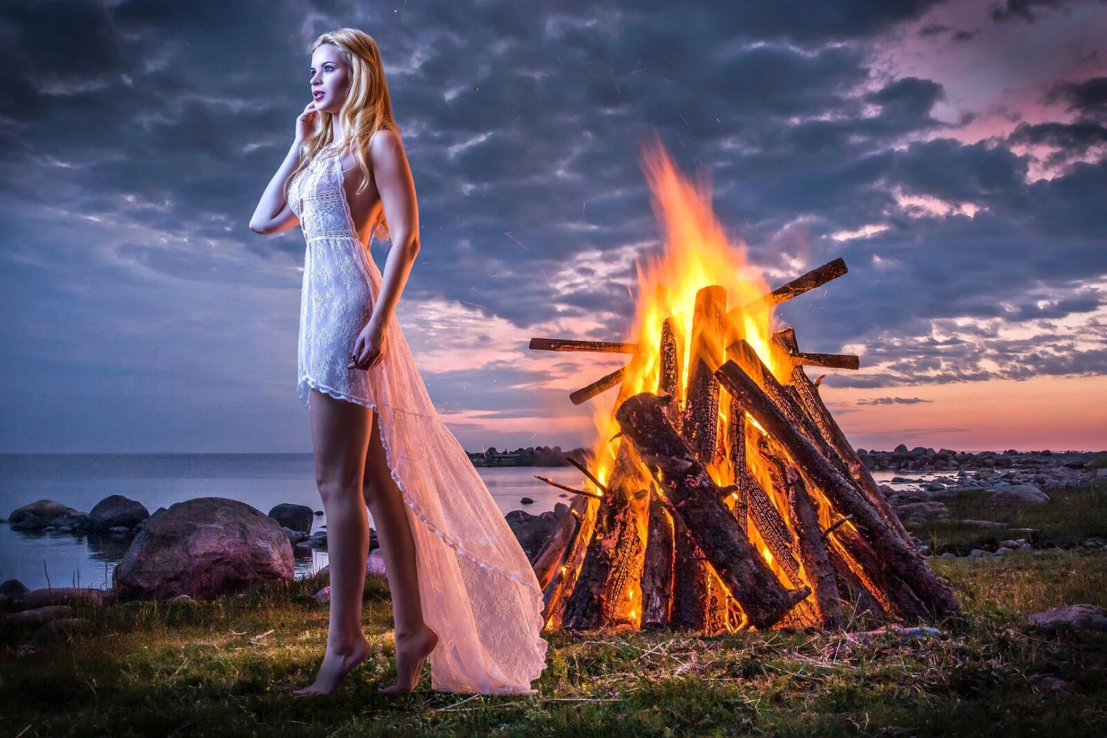 Free photo A girl in a white dress by a big fire