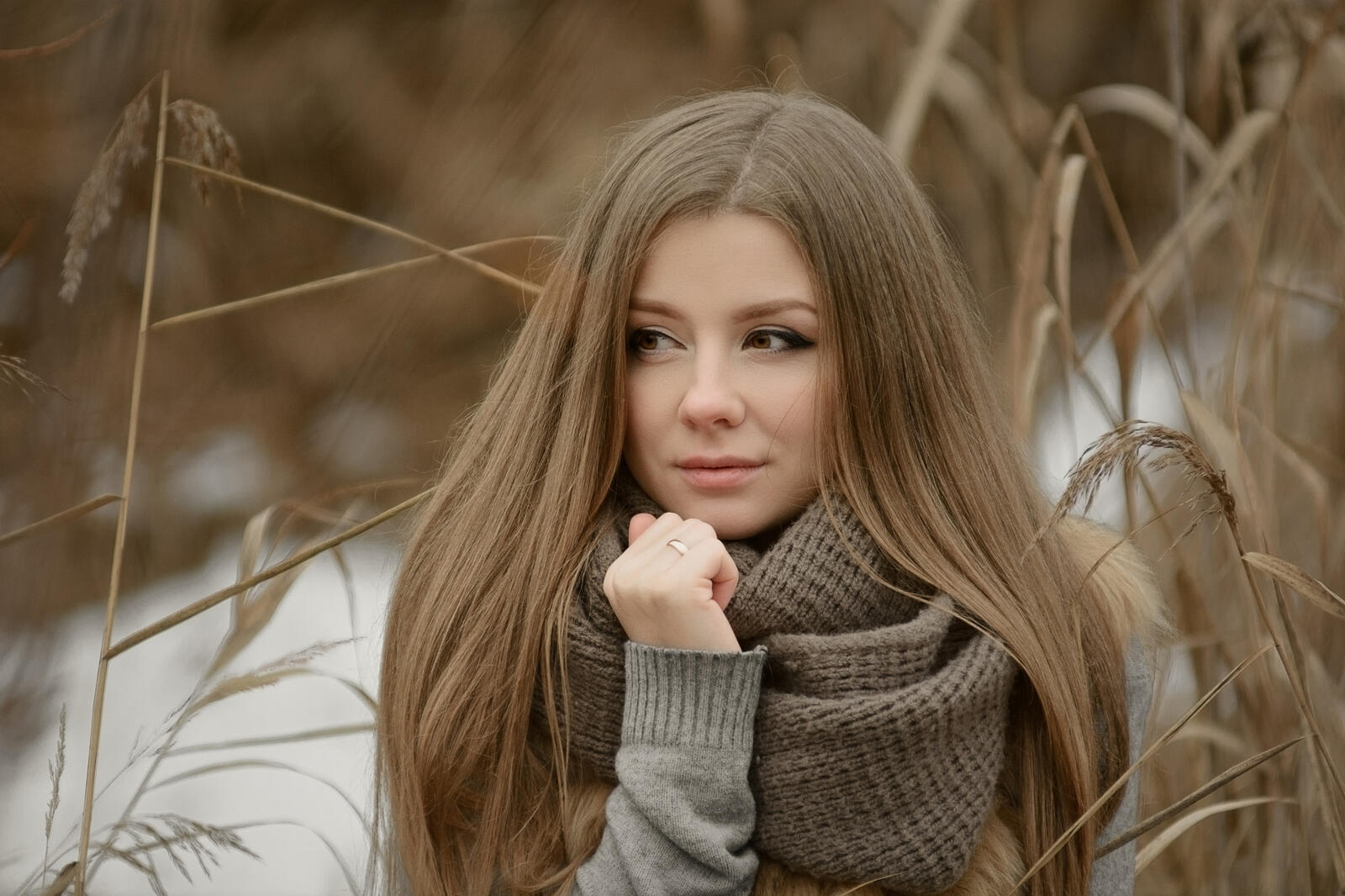 Free photo Portrait of a brown-haired woman wearing a knitted winter scarf in brown color