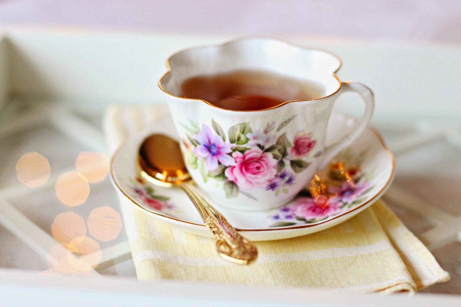 Бесплатное фото Чашка чая на блюдце с золотистой ложкой