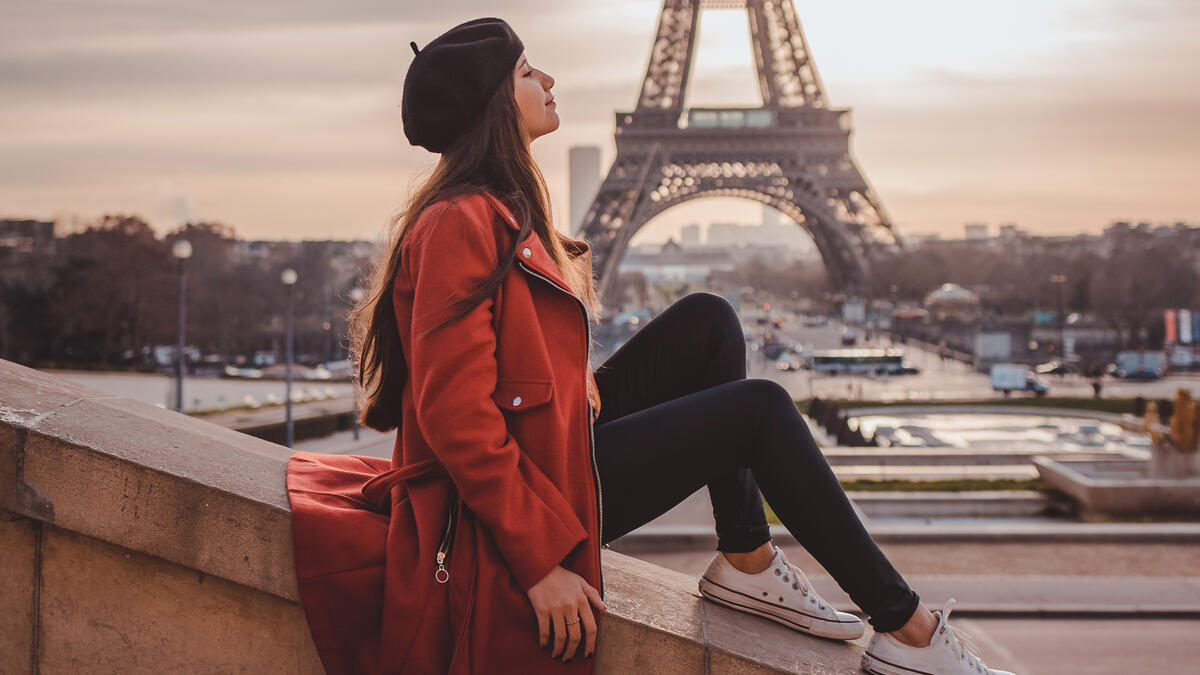 Girl in a red jacket against the background of the Eiffel Tower