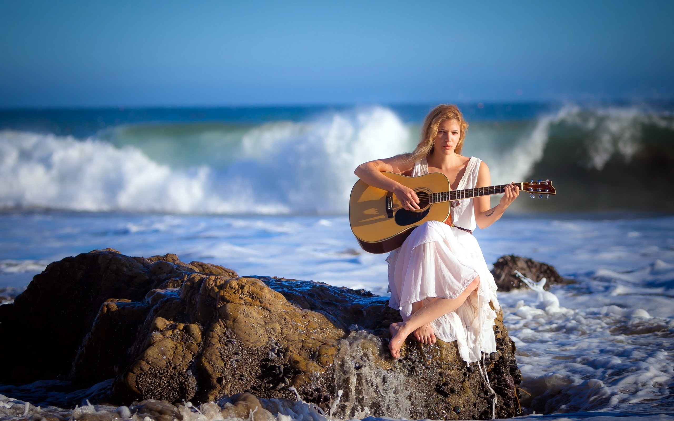 Free photo Girl in a white dress with a guitar by the sea