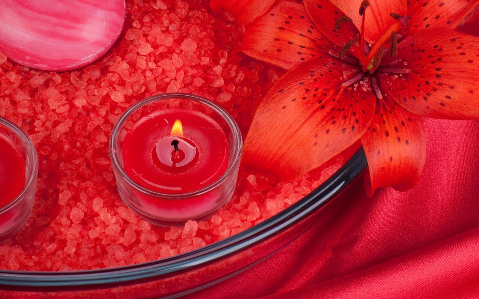 Free photo Burning candle on a red background with a lily