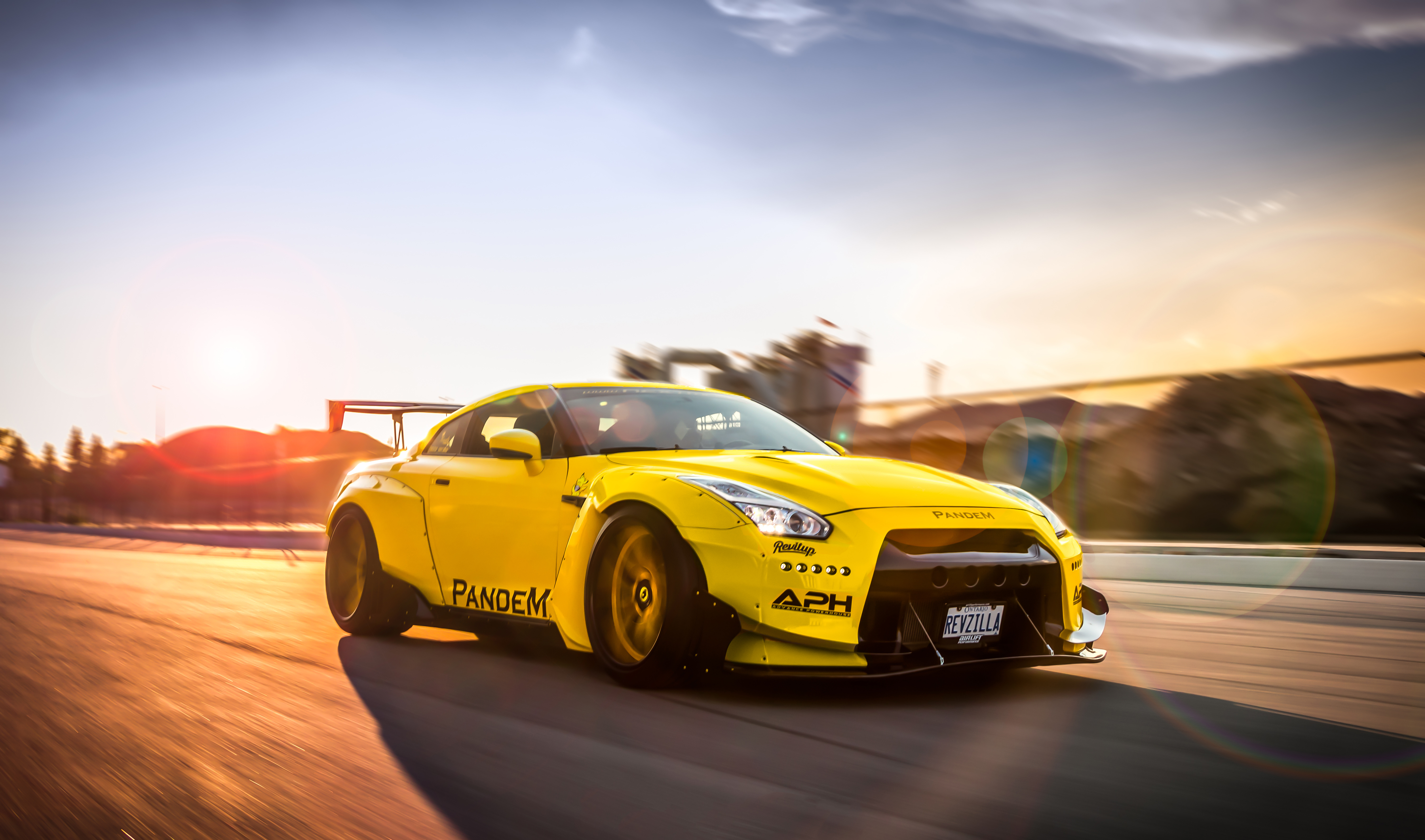 Free photo A bright yellow Nissan GTR on the move at sunset