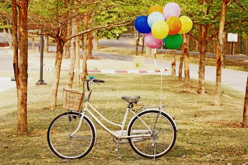 A bicycle with balloons left in a park
