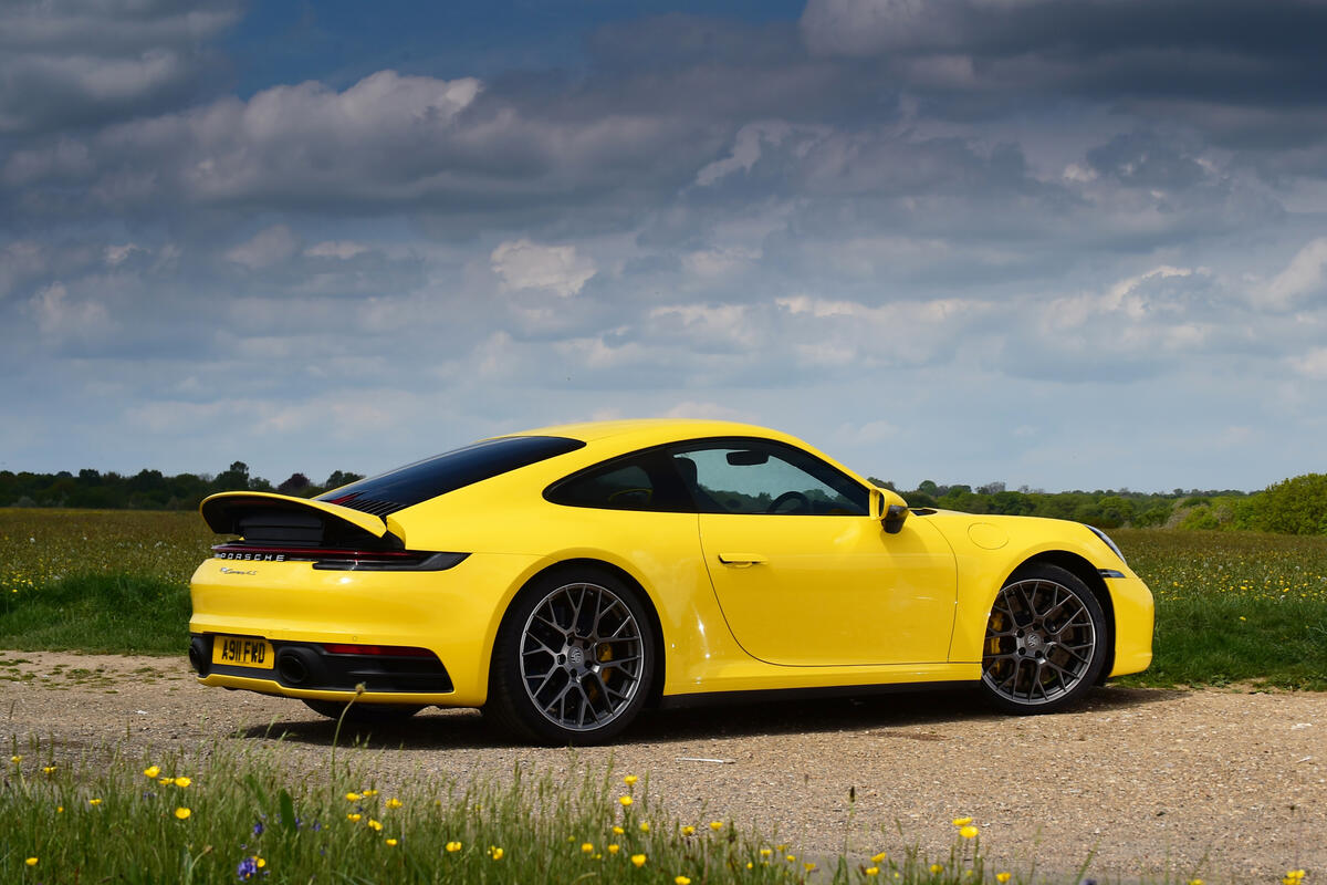 Желтый Porsche 911 с серыми дисками стоит на грунтовой дороге