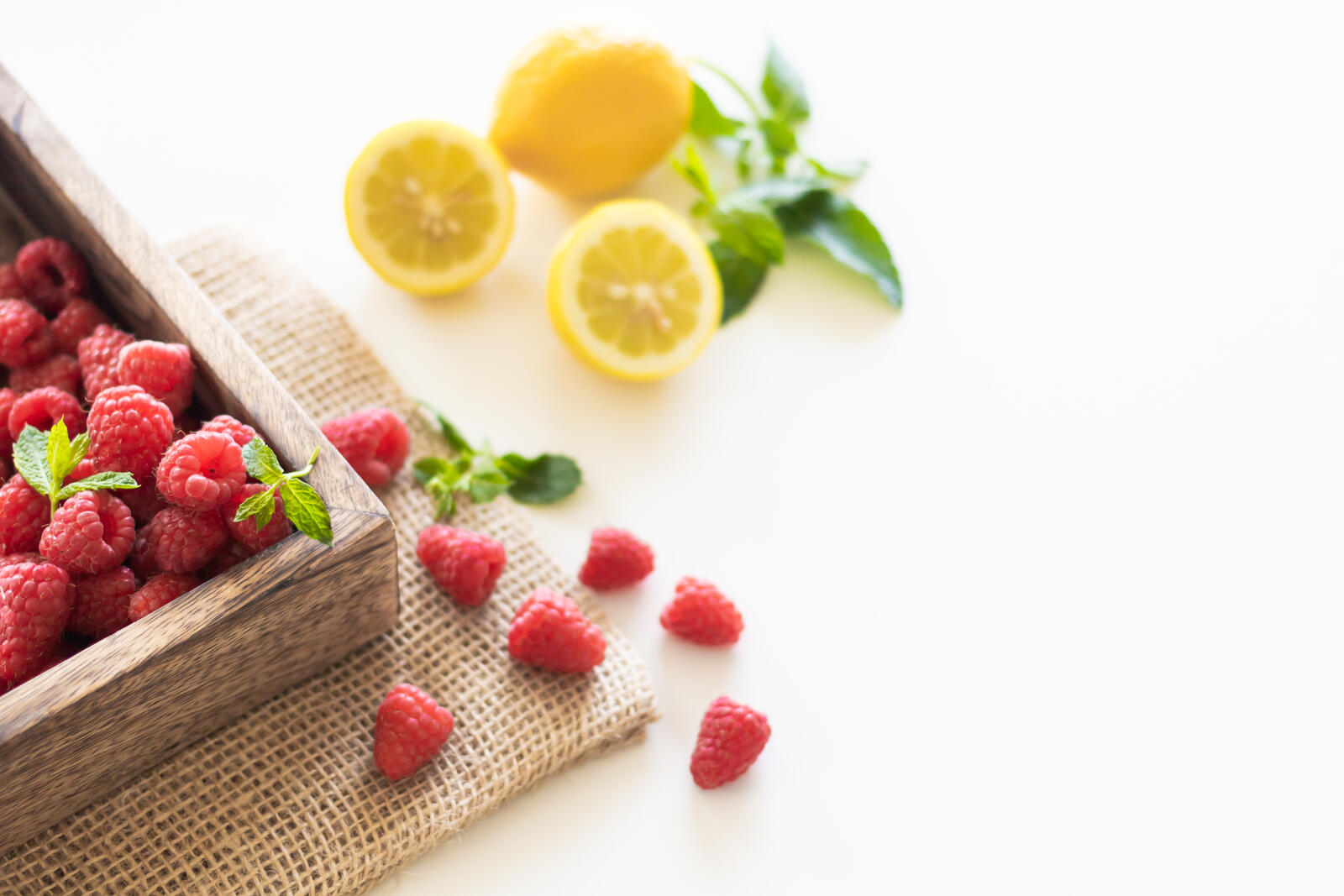Free photo Scattered berries with lemon slices on a white tabletop