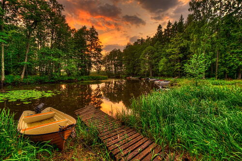 Деревянный мостик с лодкой на летнем озере