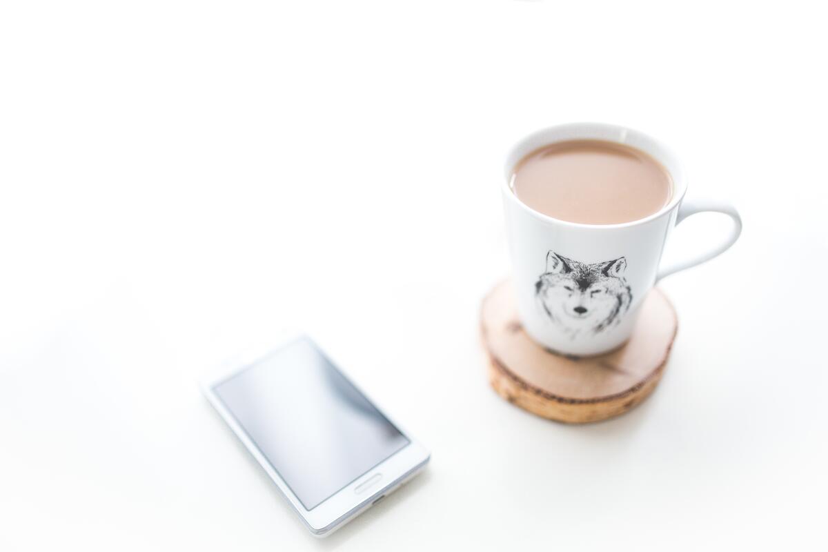 There`s a phone and a cup of coffee on the desk