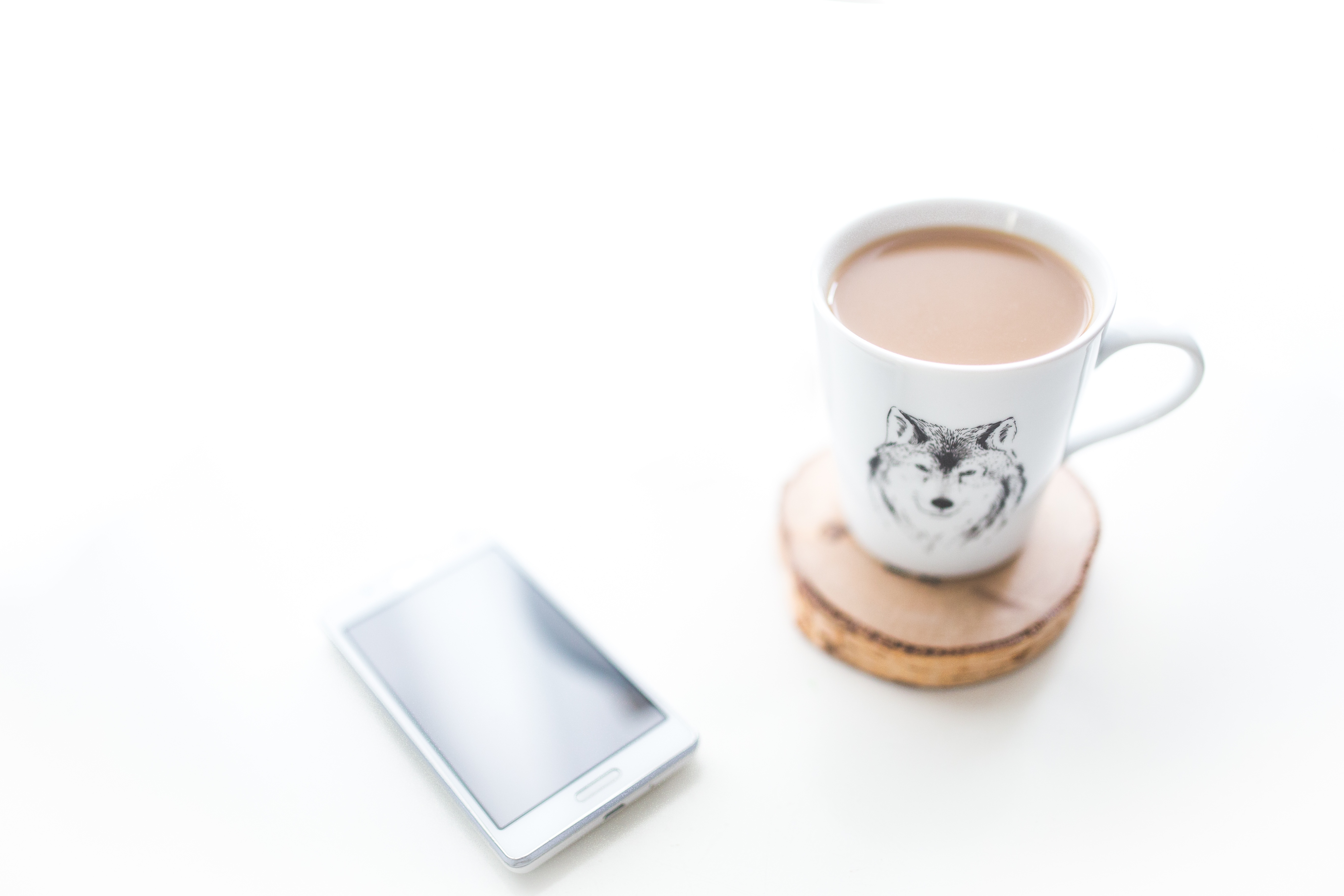 На письменном столе лежит телефон и чашка с кофе