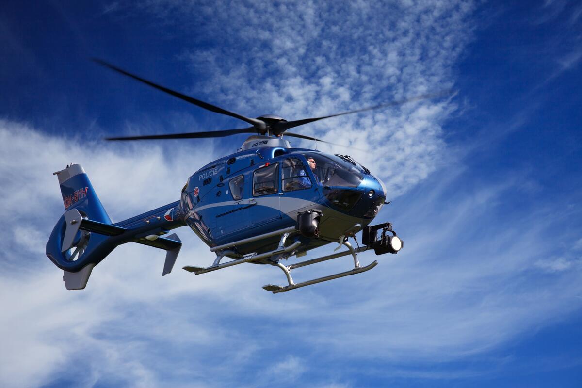 A helicopter flies against a clear sky.