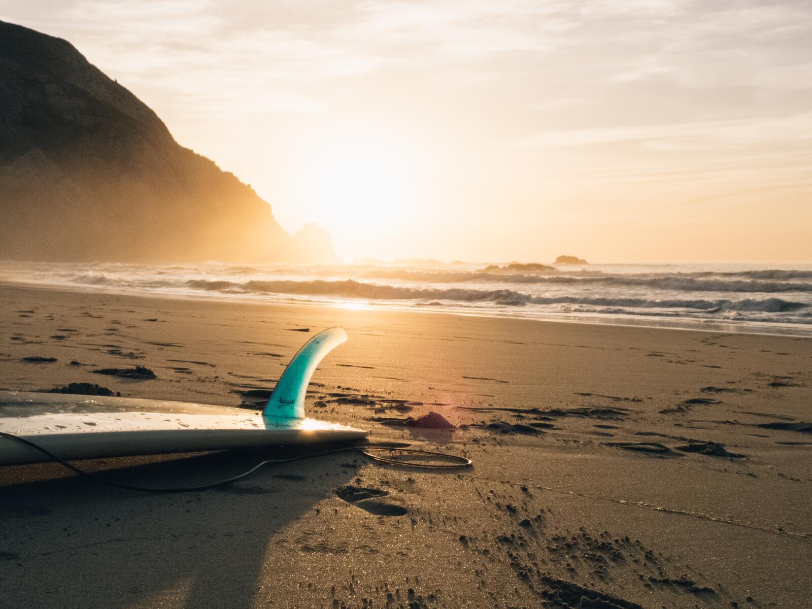 Бесплатное фото Доска для серфинга на песчаном пляже при закате солнца